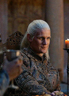 a man with long blonde hair is sitting in a chair with a candle in the background .