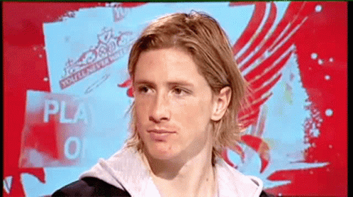 A Man With Long Blonde Hair Is Sitting In Front Of A Sign That Says Play GIF