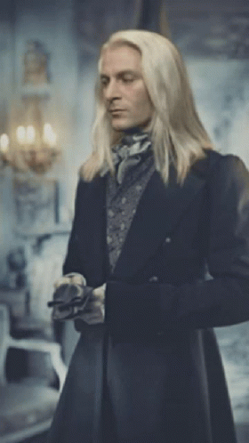 A Man With Long Blonde Hair Is Standing In A Room GIF
