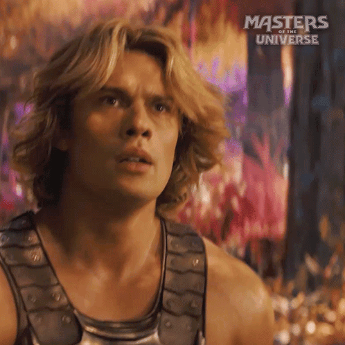 A Man With Long Blonde Hair Is Wearing A Tank Top From The Movie Masters Of The Universe GIF