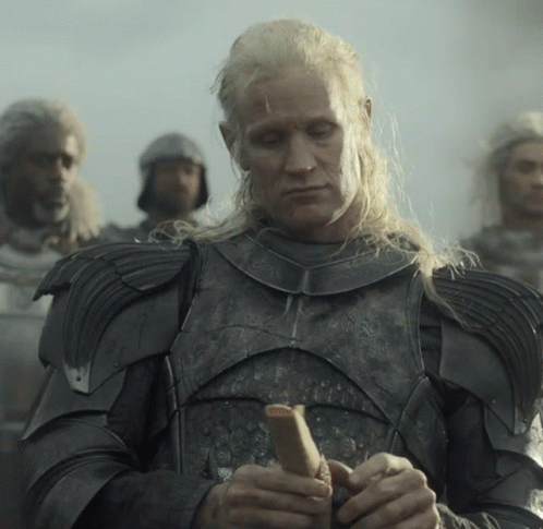 A Man With Long Blonde Hair Is Wearing Armor And Holding A Stick GIF