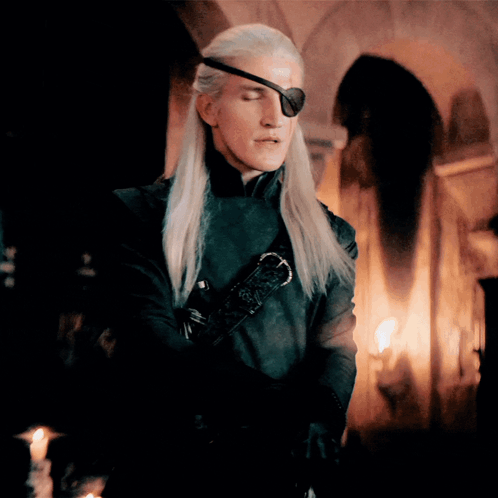 A Man With Long Blonde Hair Wearing A Black Eye Patch GIF