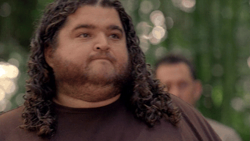 A Man With Long Curly Hair And A Beard Looks To The Side GIF