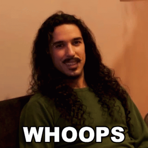 A Man With Long Curly Hair And A Mustache Is Wearing A Green Shirt That Says " Whoops " GIF