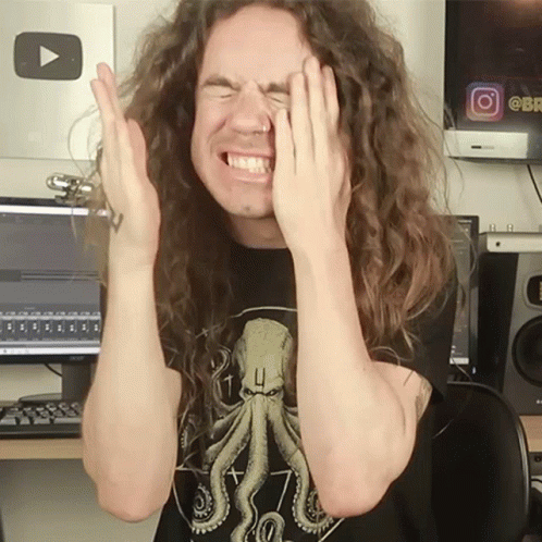 A Man With Long Curly Hair Covering His Face With His Hands GIF