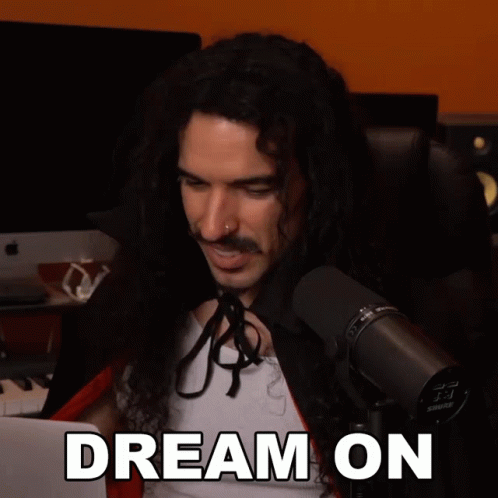 A Man With Long Curly Hair Is Sitting In Front Of A Shure Microphone GIF