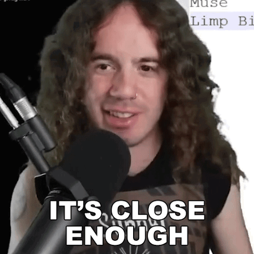 A Man With Long Curly Hair Stands In Front Of A Microphone And Says It 'S Close Enough . GIF