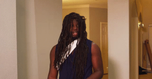 A Man With Long Dreadlocks And A White Scarf Around His Neck GIF