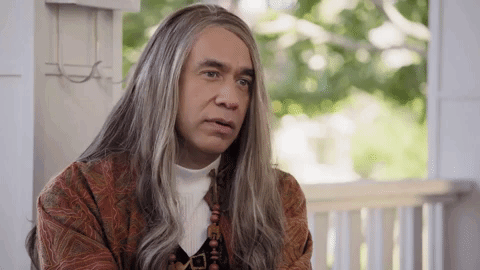 A Man With Long Gray Hair Is Sitting On A Porch . GIF