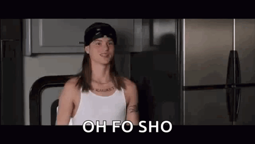 A Man With Long Hair And A Bandana Is Standing In Front Of A Refrigerator . GIF
