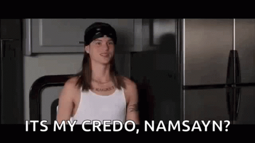 A Man With Long Hair And A Bandana On His Head Is Standing In Front Of A Refrigerator In A Kitchen . GIF