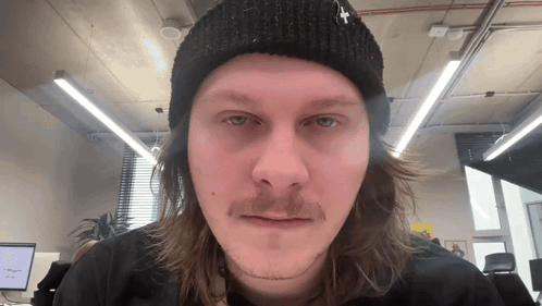 a man with long hair and a beanie with a cross on it