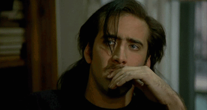 A Man With Long Hair And A Beard Has His Hand On His Face GIF