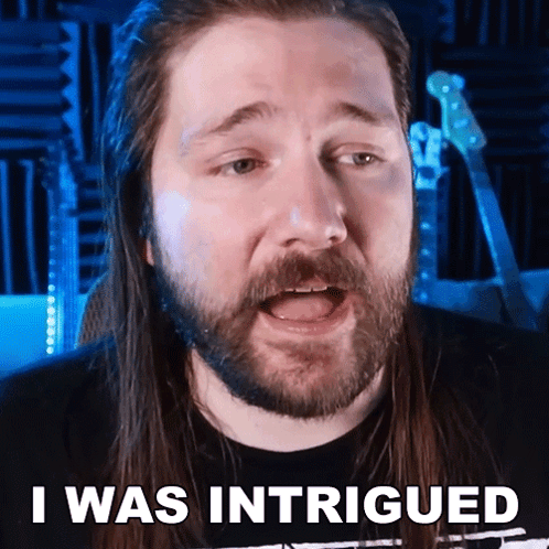 A Man With Long Hair And A Beard Has The Words I Was Intrigued Above His Head GIF