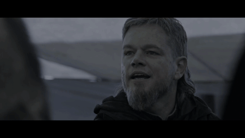 A Man With Long Hair And A Beard In A Dark Room GIF
