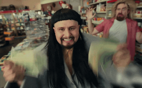 A Man With Long Hair And A Beard Is Holding A Bunch Of Money In A Store GIF