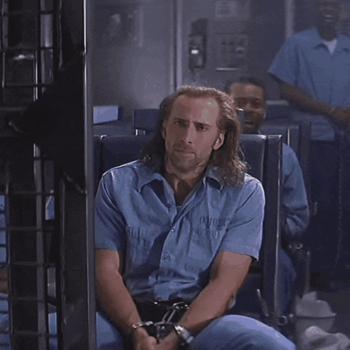 A Man With Long Hair And A Beard Is Looking At Something GIF