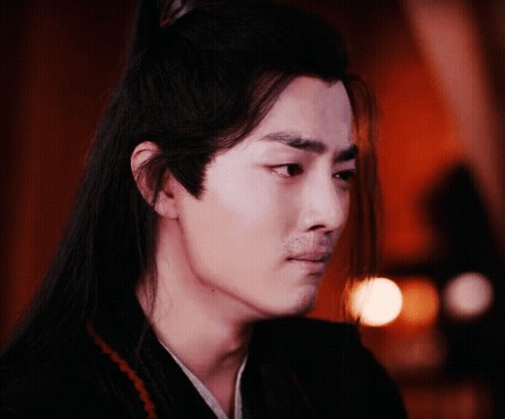 A Man With Long Hair And A Beard Is Looking At The Camera . GIF