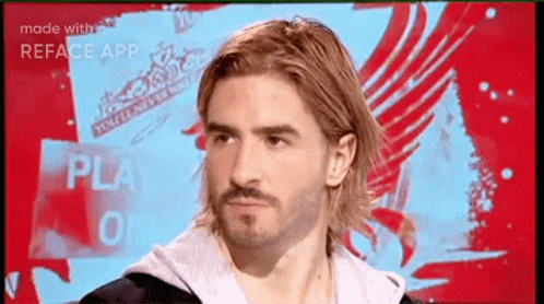 A Man With Long Hair And A Beard Is Looking At The Camera GIF