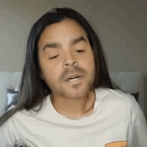 A Man With Long Hair And A Beard Is Making A Funny Face . GIF