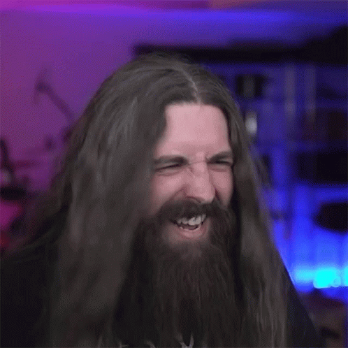A Man With Long Hair And A Beard Is Making A Horns Sign . GIF