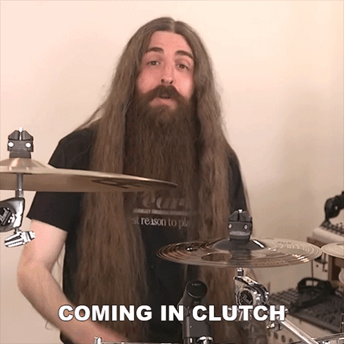 A Man With Long Hair And A Beard Is Playing Drums And The Words Coming In Clutch Are Above Him GIF