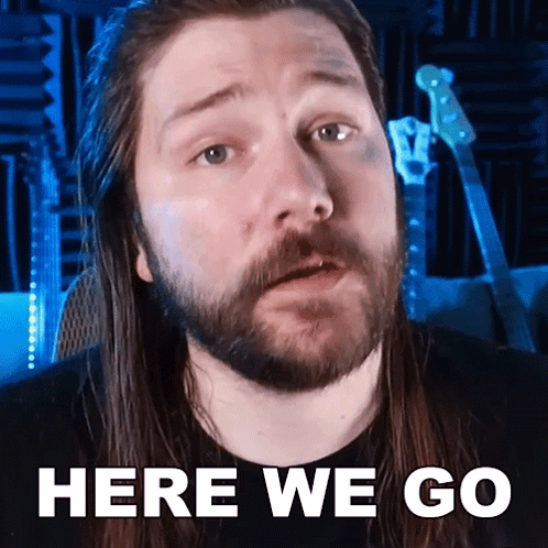 a man with long hair and a beard is saying " here we go "
