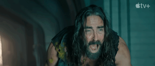 a man with long hair and a beard is screaming in front of an apple tv+ sign