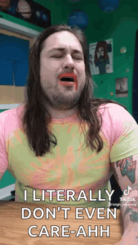 A Man With Long Hair And A Beard Is Sitting At A Table With His Mouth Open And Lipstick On His Face . GIF