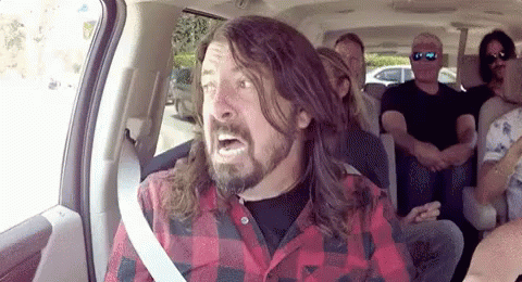 A Man With Long Hair And A Beard Is Sitting In A Car With Other People . GIF