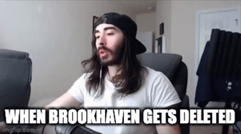 A Man With Long Hair And A Beard Is Sitting In A Chair With A Microphone . GIF