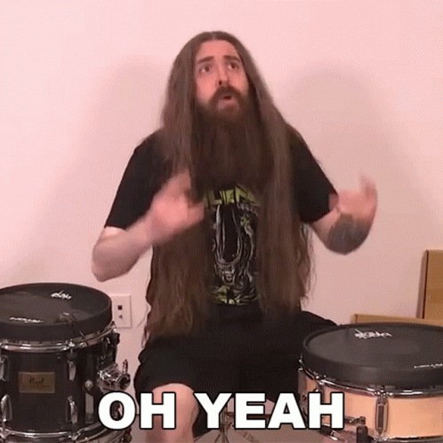 A Man With Long Hair And A Beard Is Sitting In Front Of A Drum Set And Saying Oh Yeah GIF