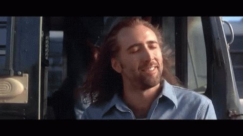 A Man With Long Hair And A Beard Is Smiling While Sitting In A Bus GIF