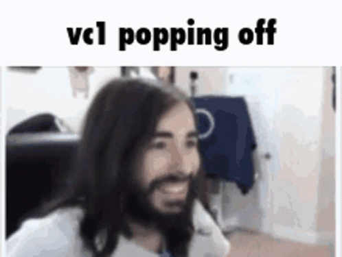 A Man With Long Hair And A Beard Is Smiling While Sitting In A Chair . GIF