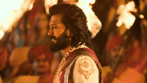 A Man With Long Hair And A Beard Is Standing In Front Of A Crowd GIF