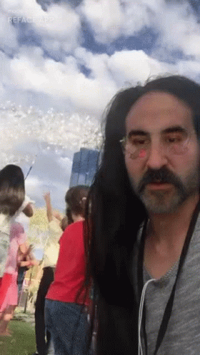 A Man With Long Hair And A Beard Is Standing In Front Of A Crowd Of People GIF