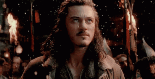 A Man With Long Hair And A Beard Is Standing In Front Of A Group Of People Holding A Torch . GIF