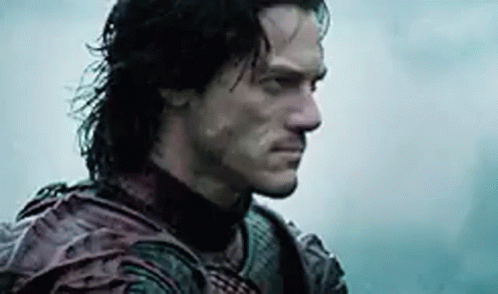 A Man With Long Hair And A Beard Is Standing In The Rain Looking At The Camera . GIF