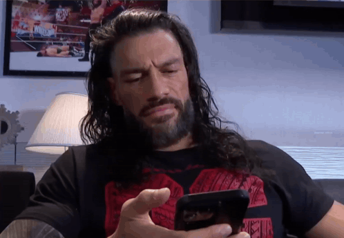 A Man With Long Hair And A Beard Is Using A Cell Phone GIF