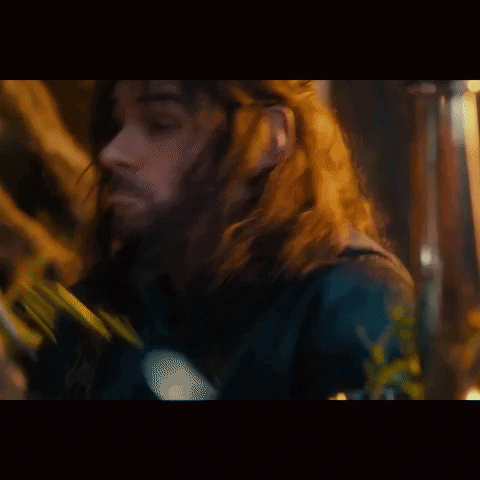 A Man With Long Hair And A Beard Is Wearing A Black Jacket . GIF