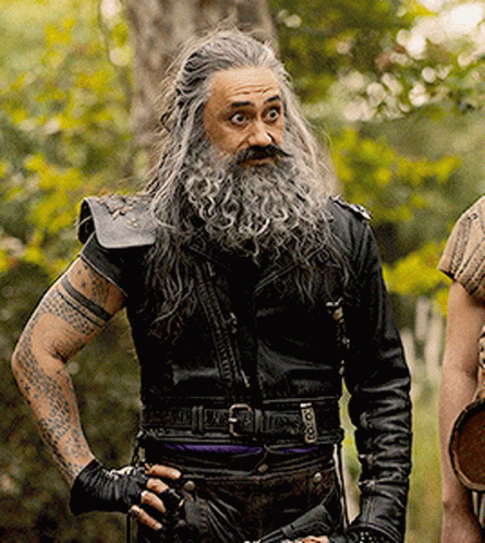 A Man With Long Hair And A Beard Is Wearing A Black Leather Jacket GIF