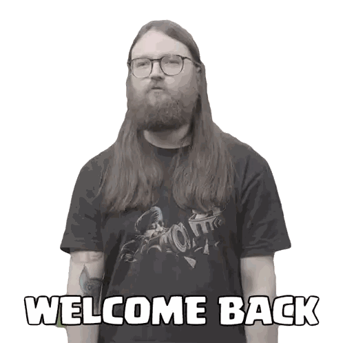 a man with long hair and a beard is wearing a black shirt that says welcome back