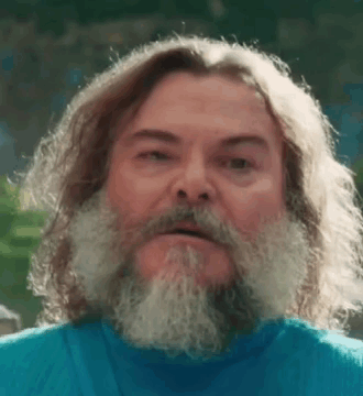 A Man With Long Hair And A Beard Is Wearing A Blue Shirt And Looking At The Camera . GIF