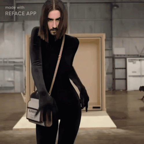 A Man With Long Hair And A Beard Is Wearing A Burberry Bag GIF
