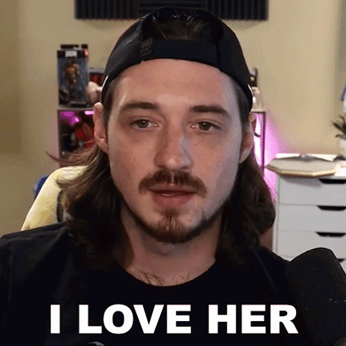 A Man With Long Hair And A Beard Is Wearing A Hat And Saying I Love Her GIF