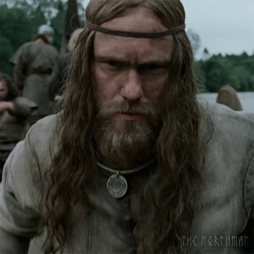 A Man With Long Hair And A Beard Is Wearing A Necklace And A Headband With The Words The Northman On It GIF