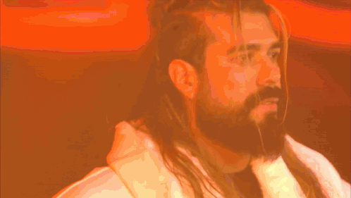 A Man With Long Hair And A Beard Is Wearing A Robe GIF