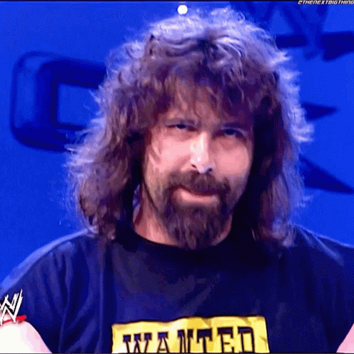 A Man With Long Hair And A Beard Is Wearing A Wanted T-Shirt GIF