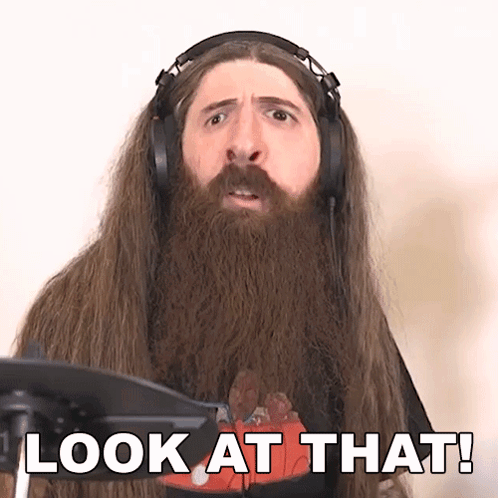 A Man With Long Hair And A Beard Is Wearing Headphones And Says Look At That GIF