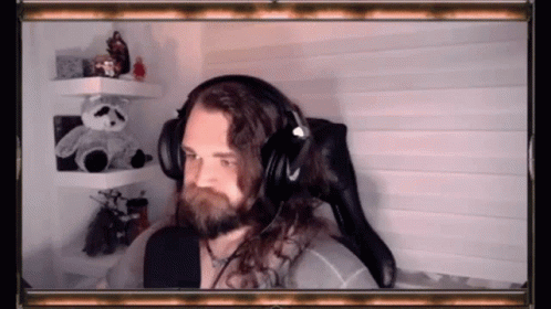 A Man With Long Hair And A Beard Is Wearing Headphones . GIF